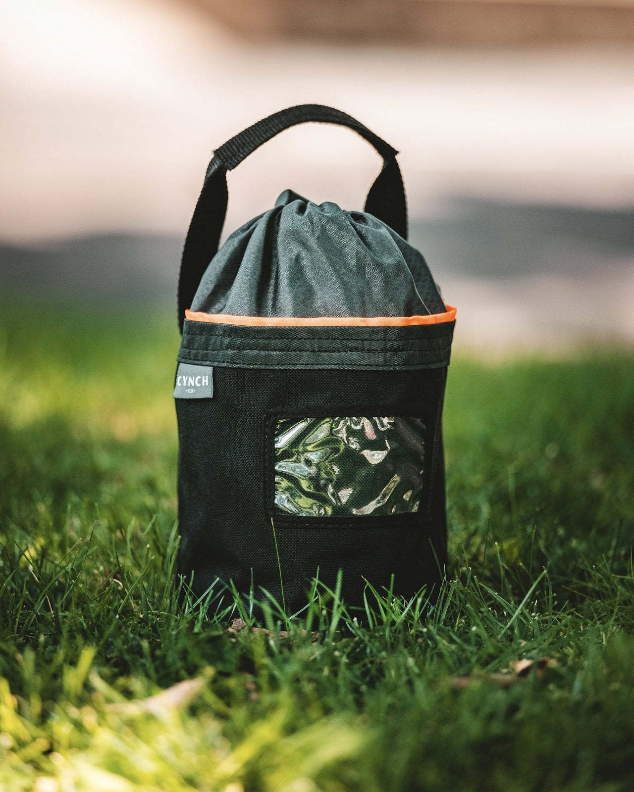 Orange-trim CYNCH bag standing in the grass